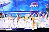 Eight Hearts2Hearts members perform choreographed dance moves on a bright stage with a beach-themed backdrop.